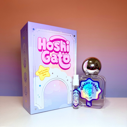 A lavender and pink outer box, a clear glass bottle Labelled "beachy peach" with a metallic silver cap, and a small travel spray vial, all set against a warm peach-to-purple gradient background.