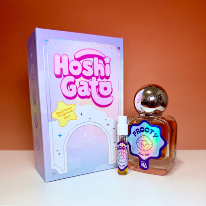 a lavender box, a rounded glass bottle of frooty perfume with round silver cap, matching sample vial, on an orange gradient background.