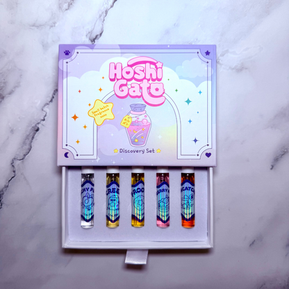 Hoshi Gato Discovery Set perfume spray vials in a decorative purple box, displayed on a light gray marble surface.